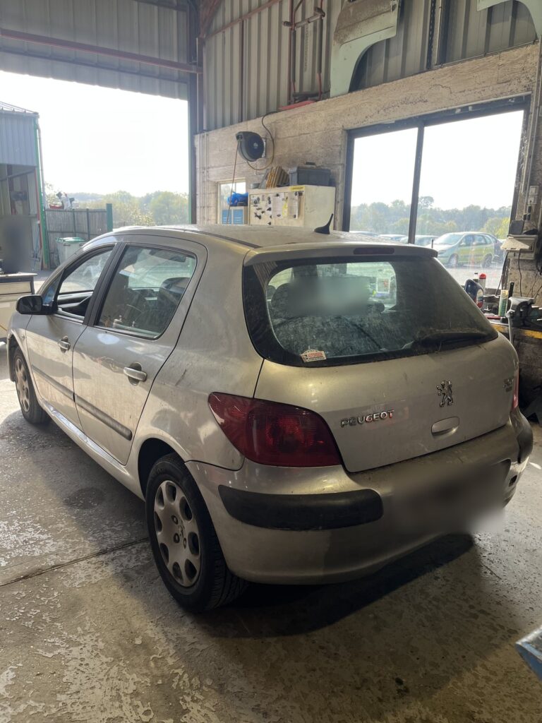 Peugeot 307 gris clair vue de trois quarts arrière dans l’atelier de la casse Jory & Fils à Esches (Oise)